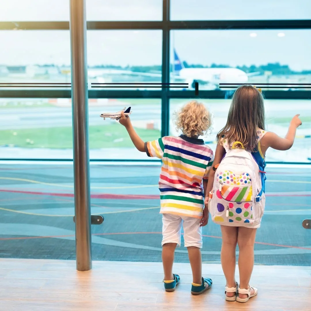 Children at airport window with toy plane and backpack